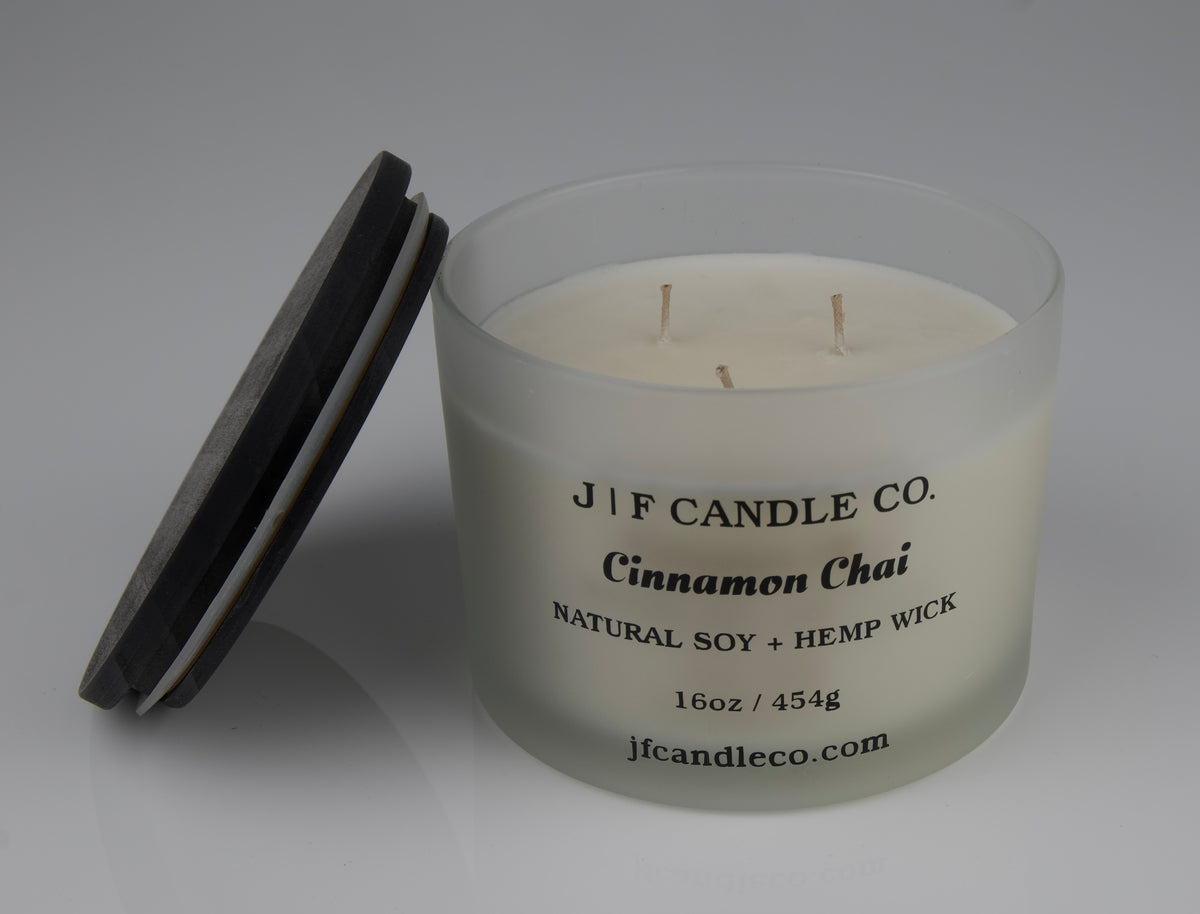 Cinnamon Chai soy candle with frosted candle jar 3 wick wick with brown wooden lid resting on side of jar