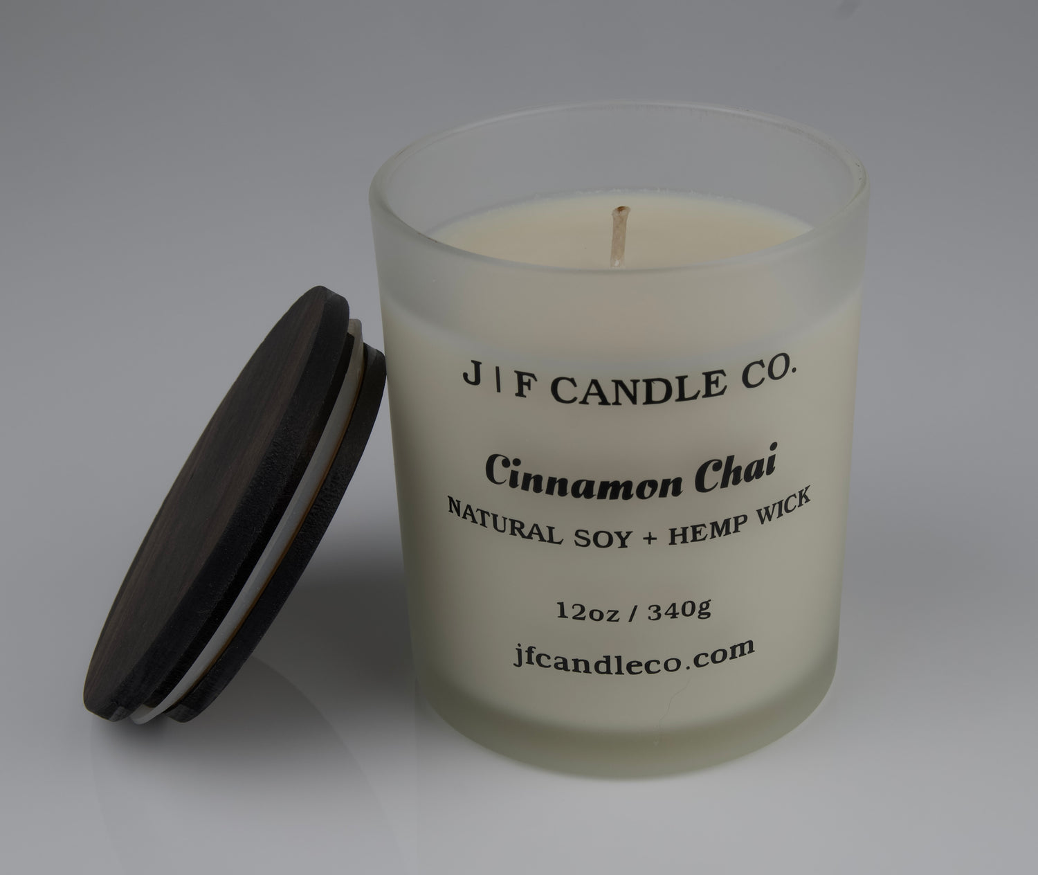 Cinnamon Chai soy candle with frosted candle jar single wick with brown wooden lid resting on side of jar