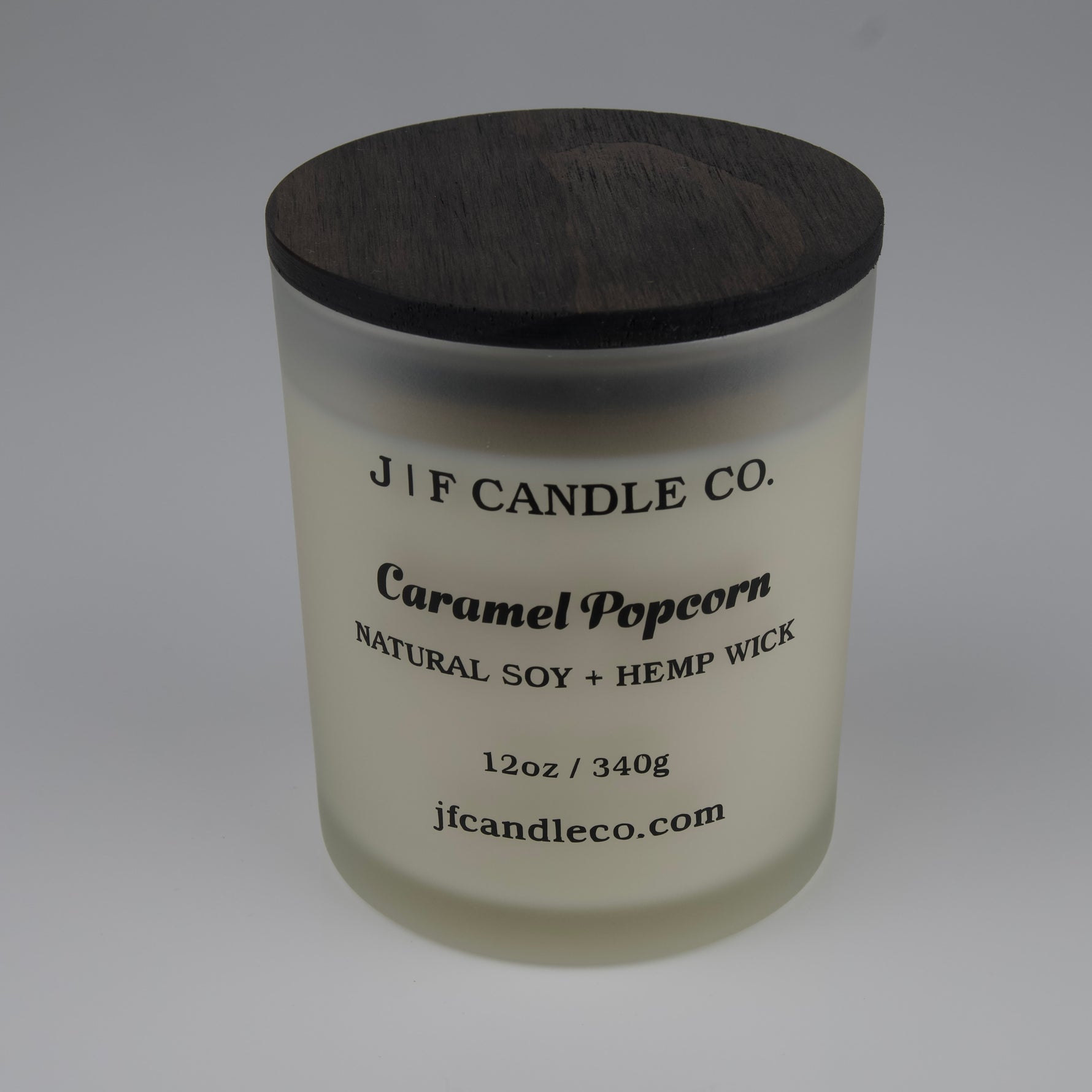 Candle with a wooden lid labeled 'J/F Candle Co. Caramel Popcorn' on a white background
