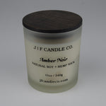 Frosted candle jar with brown lid labeled JF Candle Co. Amber Noir on a white background