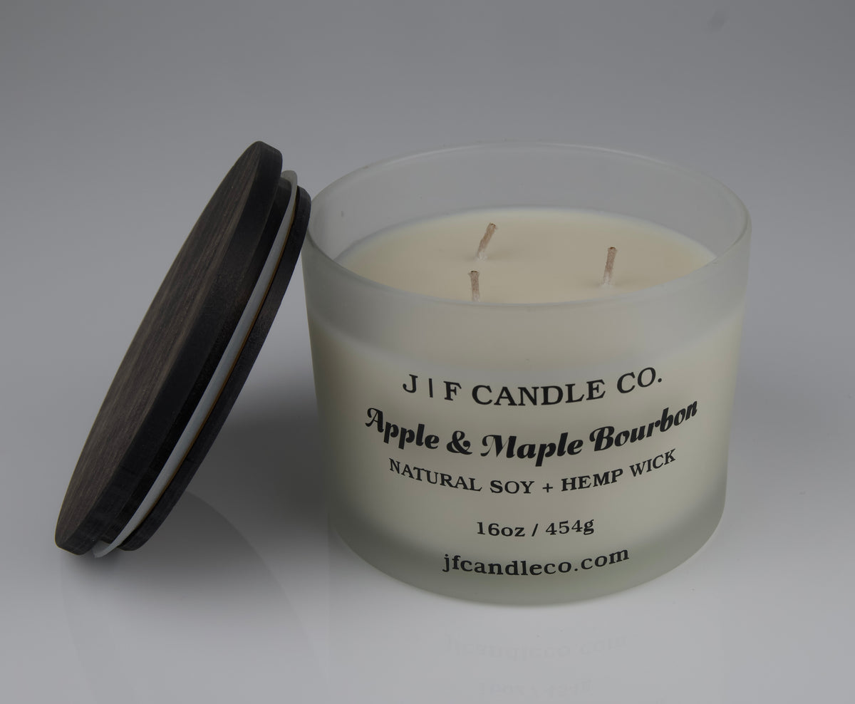 16oz Frosted candle jar with brown lid resting on side and labeled Apple and Maple Bourbon