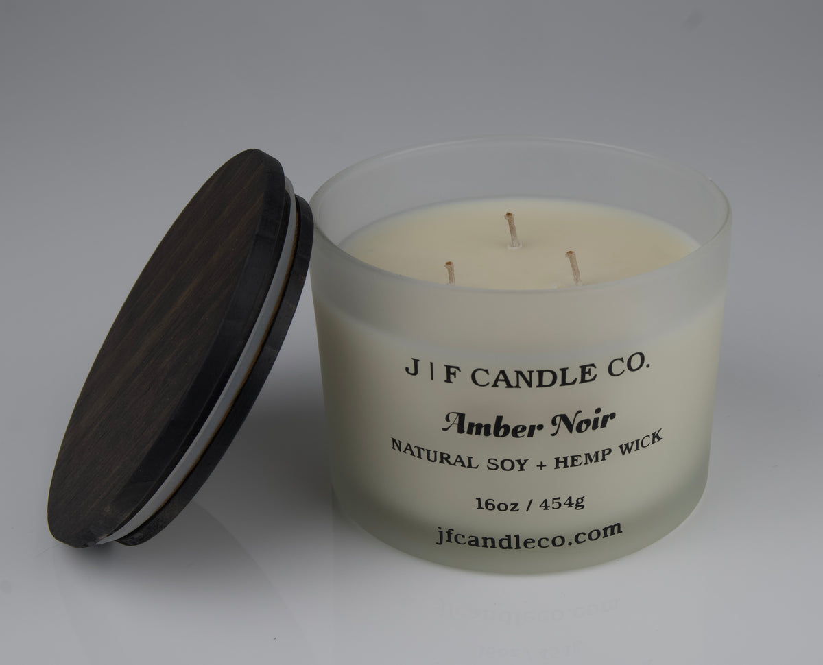 Candle with a brown lid labeled 'JF Candle Co. Amber Noir'