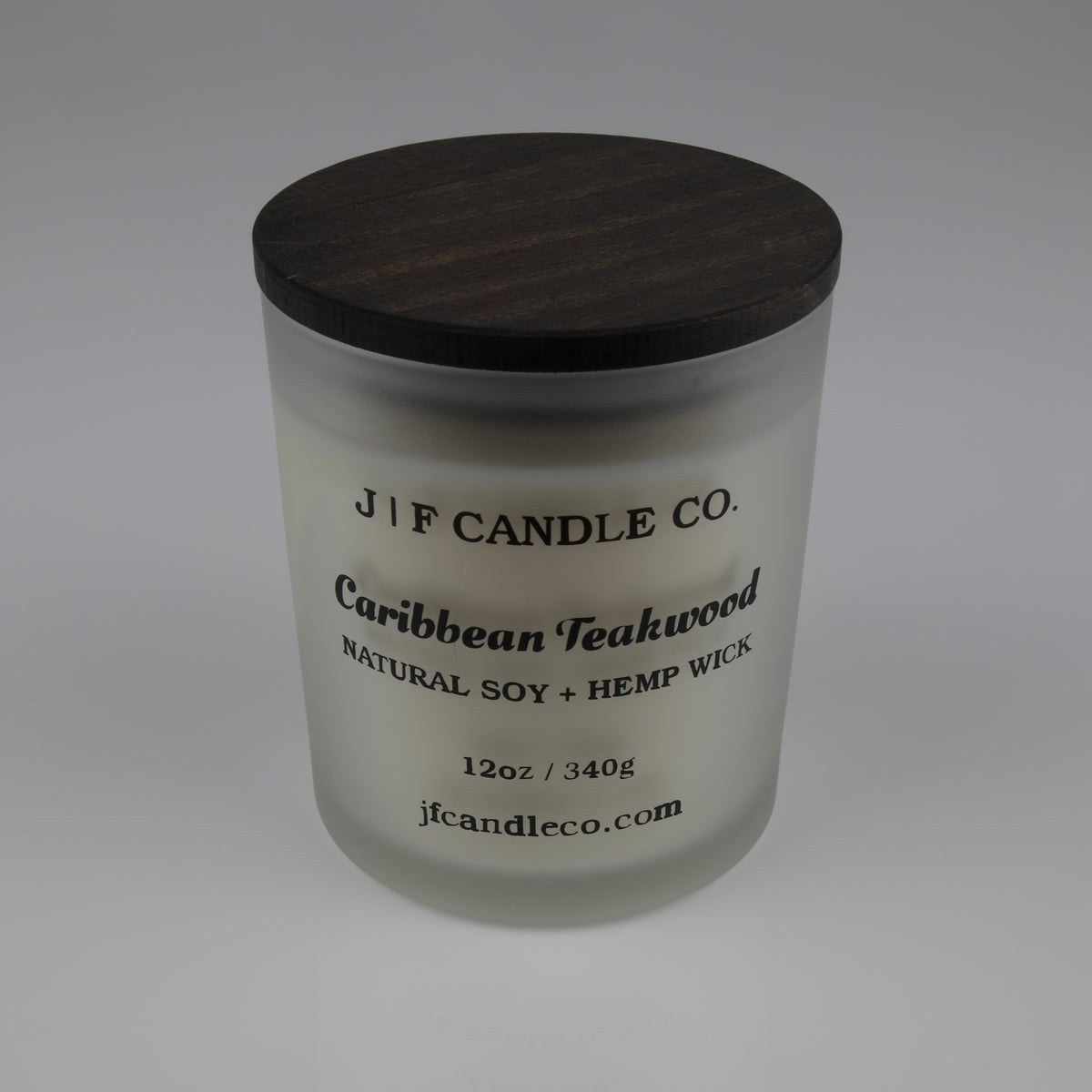 Frosted glass candle with wooden lid labeled 'J|F Candle Co. Caribbean Teakwood'