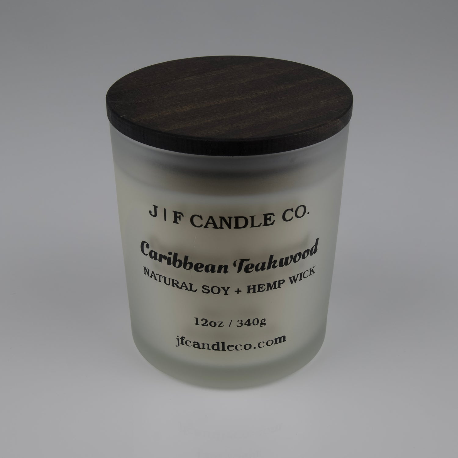 Frosted glass candle with wooden lid labeled 'J|F Candle Co. Caribbean Teakwood'