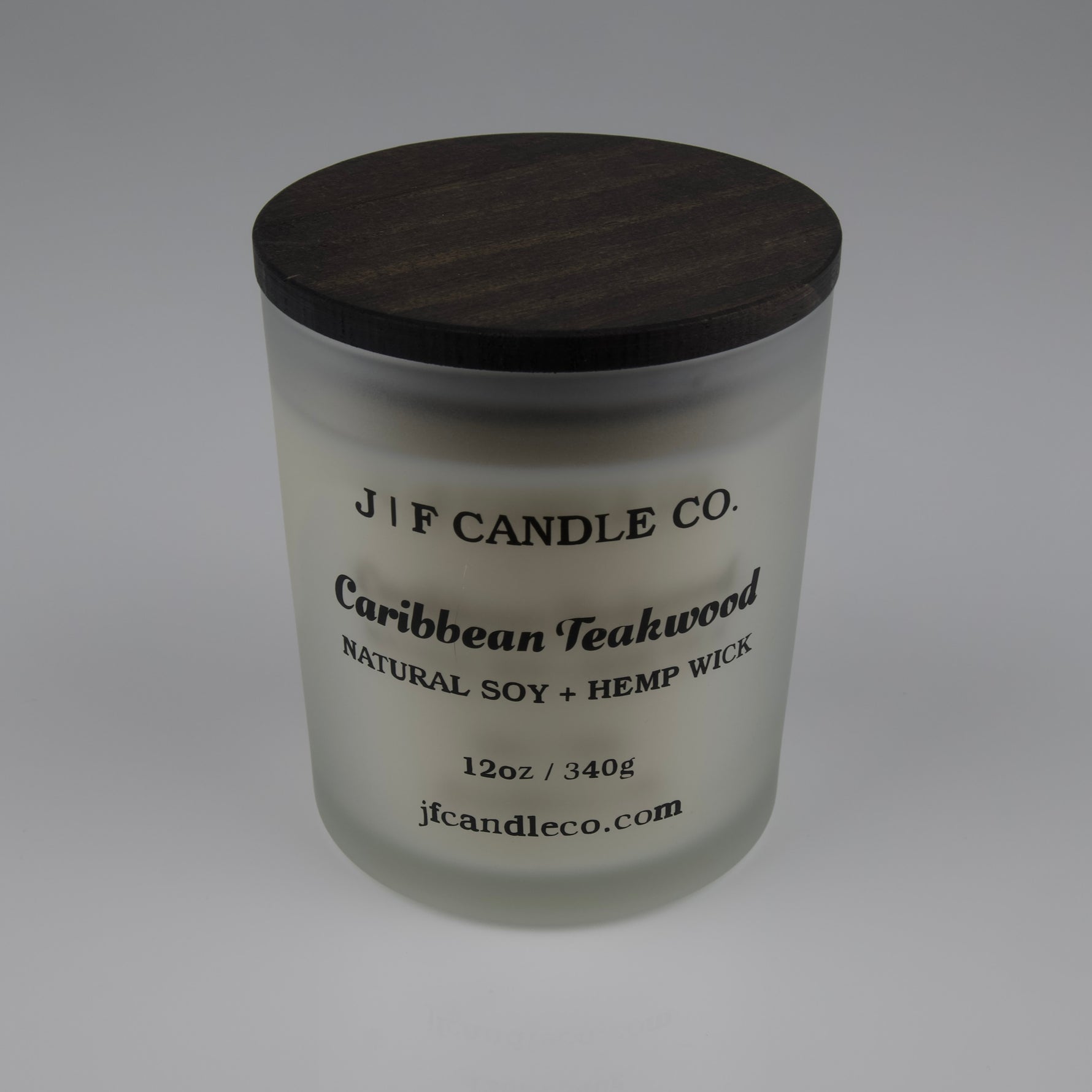 Frosted glass candle with wooden lid labeled 'J|F Candle Co. Caribbean Teakwood'