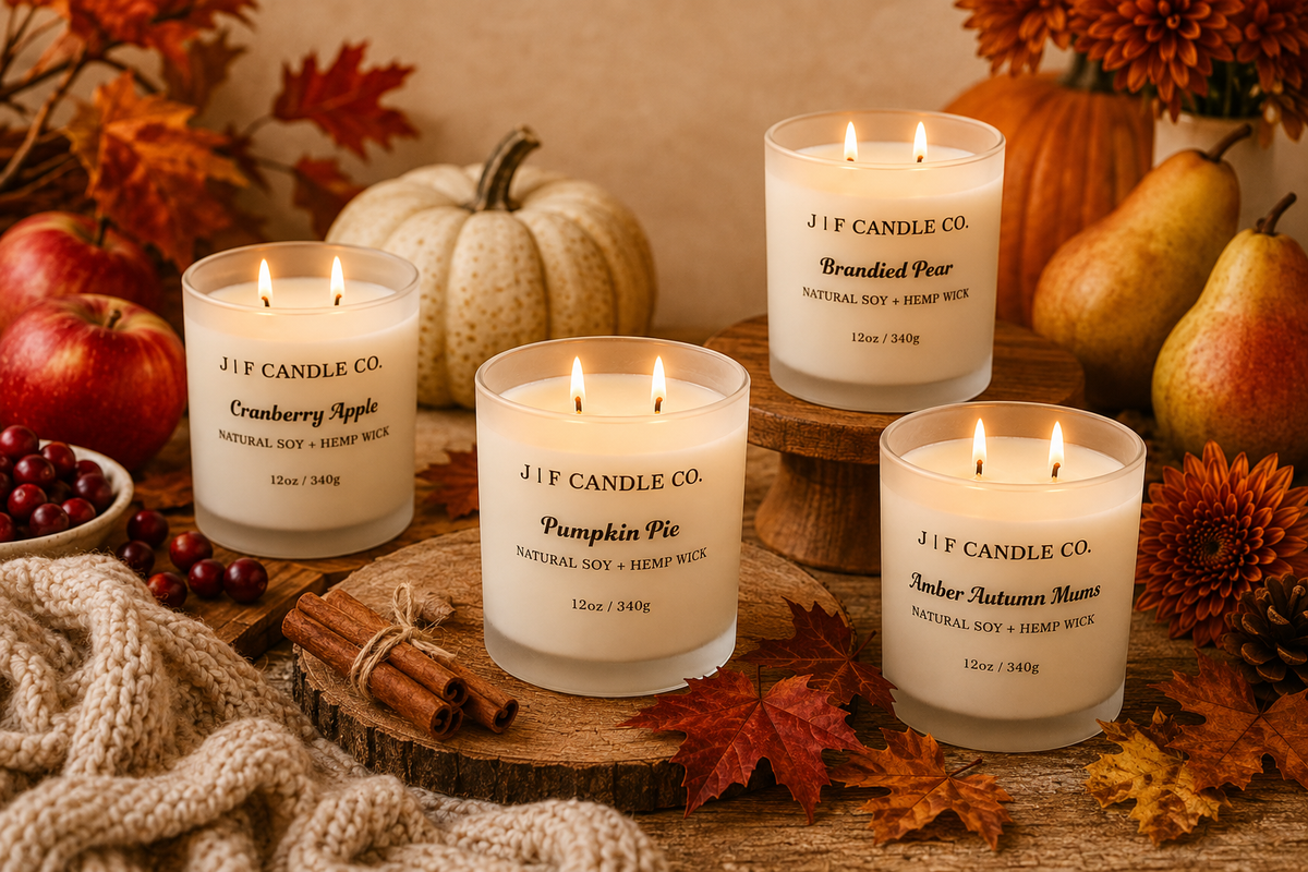 Four J | F Candle Co. fall soy candles featuring Pumpkin Pie, Cranberry Apple, Brandied Pear, and Amber Autumn Mums surrounded by cozy autumn décor.