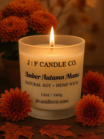 J | F Candle Co. Amber Autumn Mums natural soy candle with hemp wick, photographed with orange mums and fall leaves, warm cozy autumn home décor scene.