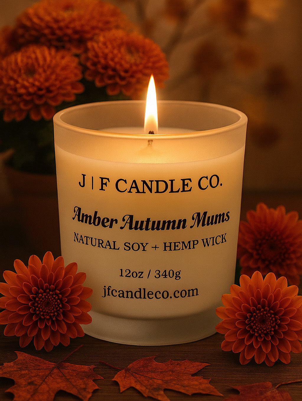J | F Candle Co. Amber Autumn Mums natural soy candle with hemp wick, photographed with orange mums and fall leaves, warm cozy autumn home décor scene.