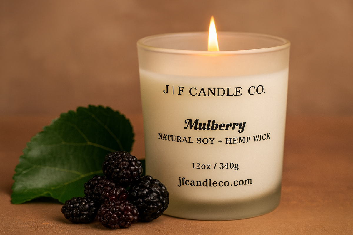 Luxury Mulberry soy candle by J | F Candle Co. with a glowing flame, surrounded by fresh mulberries on a warm background, natural soy and hemp wick, eco-friendly handmade candle for a cozy and elegant home fragrance.