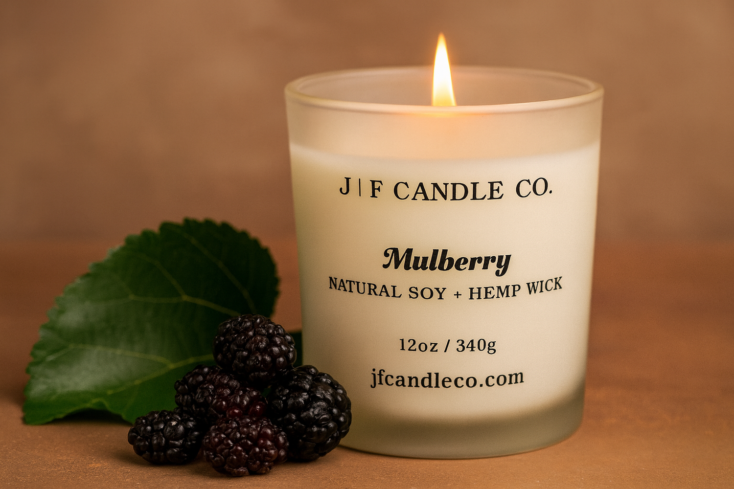 Luxury Mulberry soy candle by J | F Candle Co. with a glowing flame, surrounded by fresh mulberries on a warm background, natural soy and hemp wick, eco-friendly handmade candle for a cozy and elegant home fragrance.