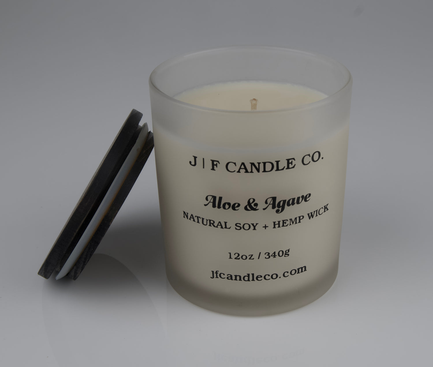 JF Candle Co. 12oz Aloe and Agave soy candle with single hemp wick in frosted glass jar, dark wooden lid resting beside it.