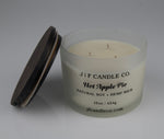 Hot Apple Pie Soy Candle by JF Candle Co. in a frosted glass jar with wooden lid resting on side of jar, 16oz hand-poured natural soy wax with hemp wick.