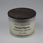 Candle jar with wooden lid labeled 'J/F Candle Co. Caramel Popcorn' on a white background