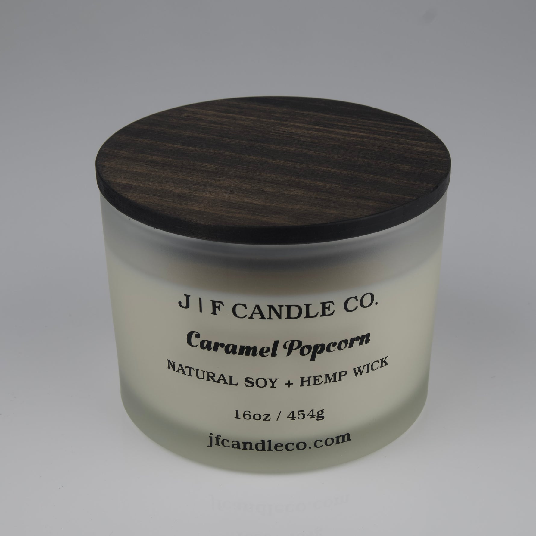 Candle jar with wooden lid labeled 'J/F Candle Co. Caramel Popcorn' on a white background