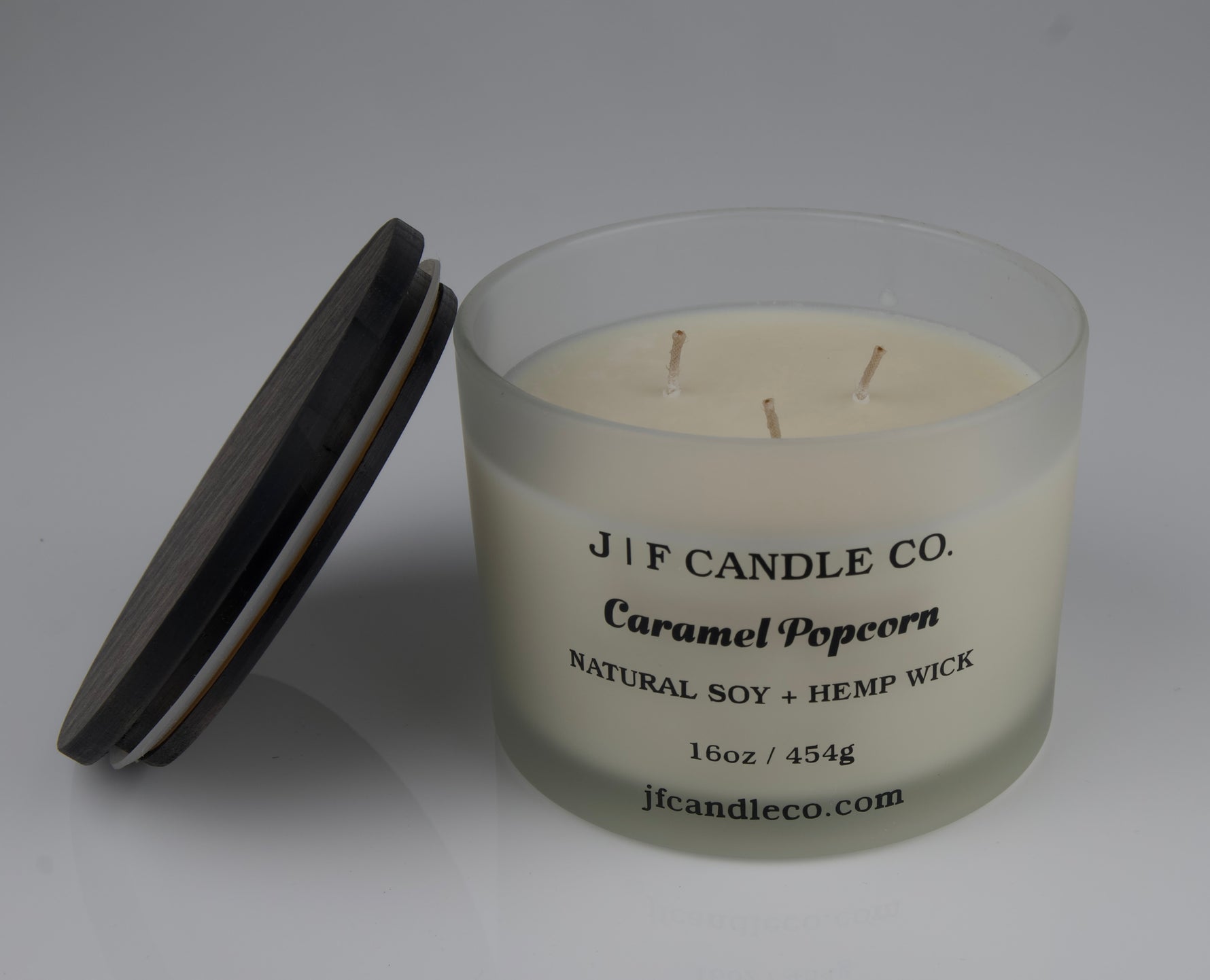 Candle with a brown wooden lid labeled 'JIF CANDLE CO. Caramel Popcorn' on a gray background