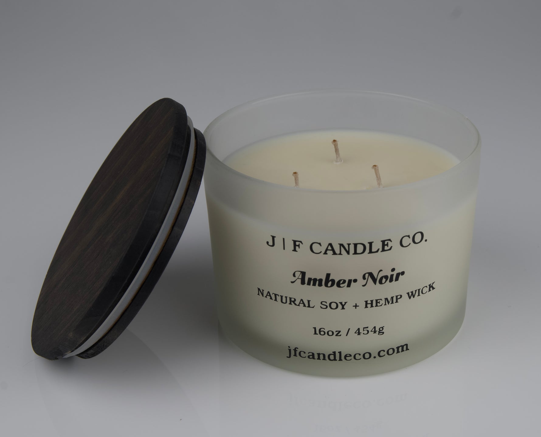 Candle with a brown lid labeled 'JF Candle Co. Amber Noir'