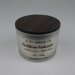 16oz Frosted glass candle with wooden lid labeled 'J|F Candle Co. Caribbean Teakwood'