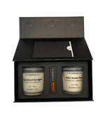 An open black gift box from J | F Candle Co. contains two frosted glass soy candles labeled “Peppermint & Eucalyptus” and “Amber Autumn Mums,” with a box of matches placed neatly in the center. The box has a clean matte finish and a minimalist insert card, photographed against a plain white background.