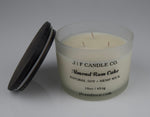JF Candle Co. 16oz Almond Rum Cake soy candle with three hemp wicks in frosted glass jar, dark wooden lid resting beside it.