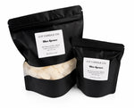 J | F Candle Co. Blue Spruce wax melts in 8 oz and 2 oz black stand-up pouches on a clean white background