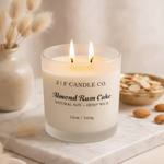 J | F Candle Co. Almond Rum Cake 12 oz natural soy candle lit on marble surface with almonds and warm luxury styling