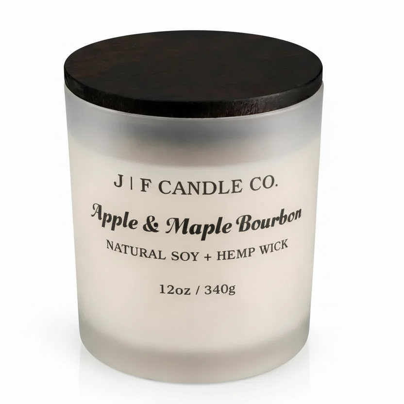J | F Candle Co. Apple & Maple Bourbon soy candle in a frosted glass jar with a dark wooden lid, shown on a clean white background with a soft reflection beneath the base.