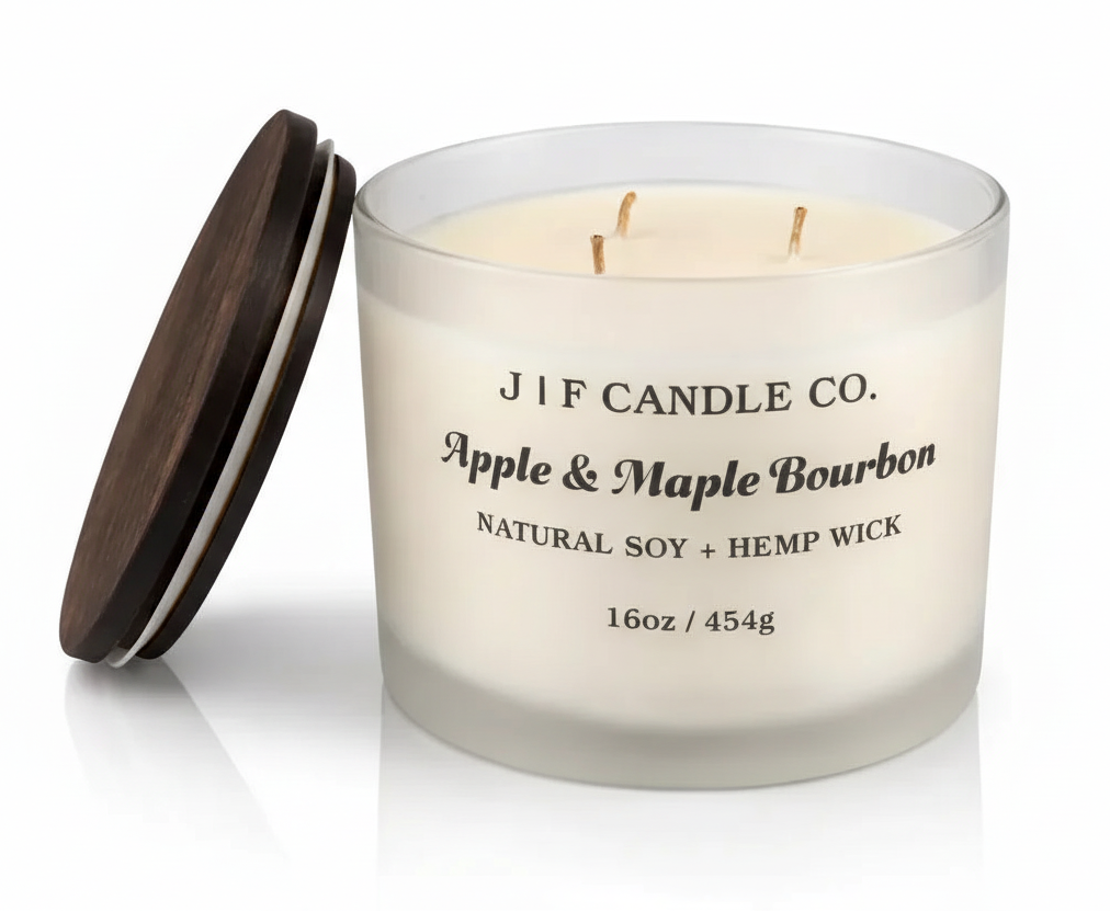 Luxury frosted glass J | F Candle Co. Apple & Maple Bourbon 16oz soy candle with wooden lid resting beside jar and a soft reflective surface beneath.