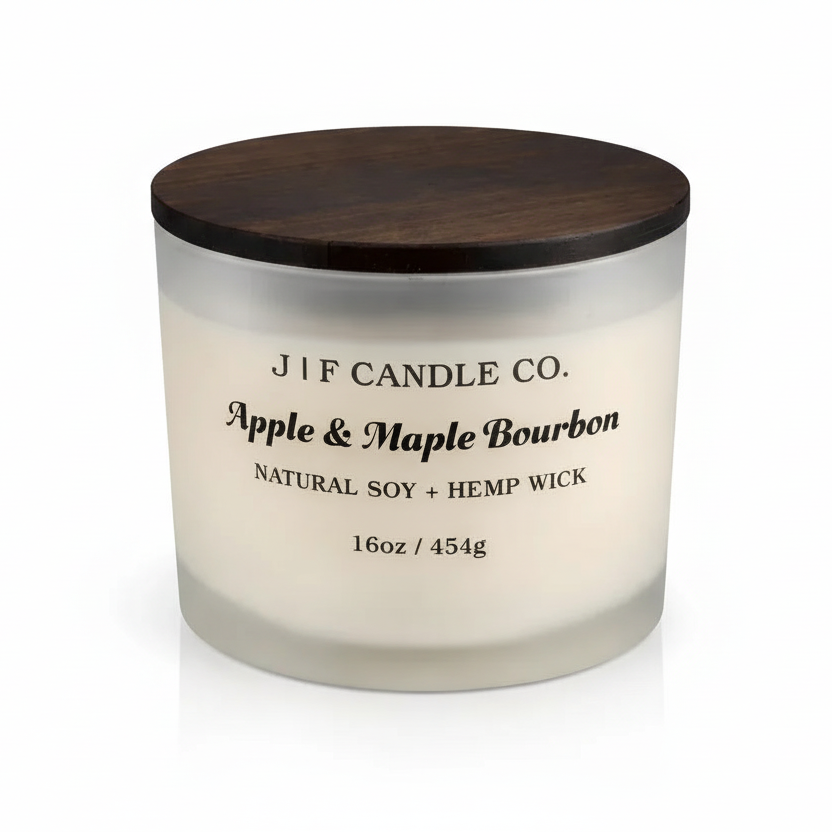 JF Candle Co. Apple & Maple Bourbon 16oz soy candle in a frosted glass jar with wooden lid, clean studio background and soft reflective surface.