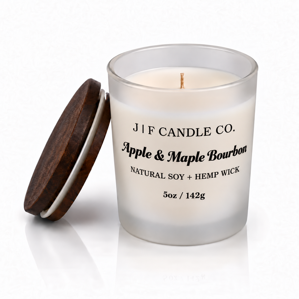 Apple & Maple Bourbon 5oz single-wick soy candle with original scent lettering and a straight divider matching the height of J and F, frosted glass, wooden lid and soft reflection.