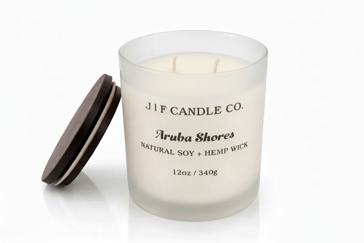 J | F Candle Co. Aruba Shores 12oz soy candle in a frosted glass jar with wooden lid resting beside it, shown on a clean white background with a soft reflection beneath the candle.