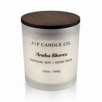Frosted glass J | F Candle Co. Aruba Shores soy candle with dark wooden lid, softly reflected on a clean white surface for a minimalist luxury product presentation.