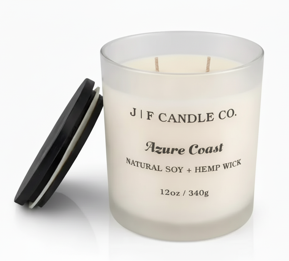 Luxury frosted glass soy candle labeled “Azure Coast” by J | F Candle Co., shown with wooden lid beside the jar and a soft reflective base on a clean white background.