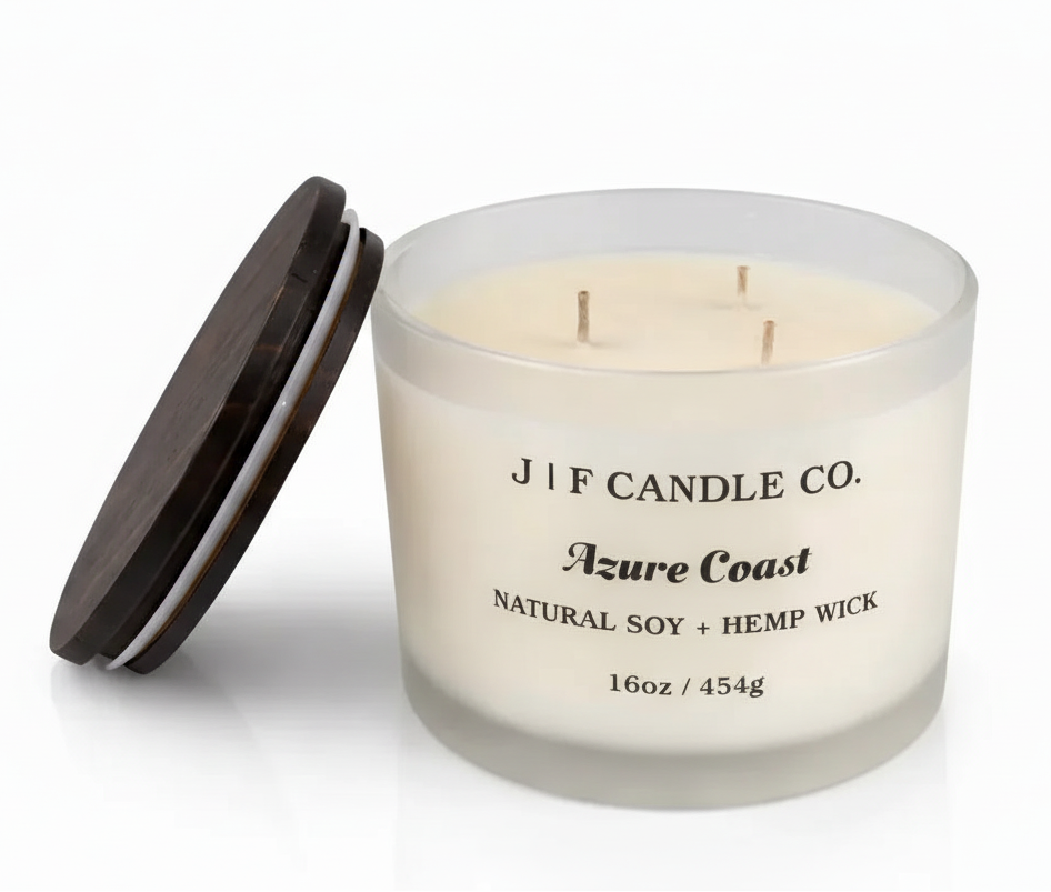 16 oz J | F Candle Co. Azure Coast soy candle in a frosted glass jar with three wicks and a wooden lid resting beside it, isolated on a clean white background with a soft reflective surface for a polished, luxury presentation.