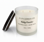 J | F Candle Co. Baby Powder 12oz soy candle in frosted glass jar with wooden lid beside candle and soft reflection on a clean white background.