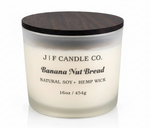 J F Candle Co. Banana Nut Bread soy candle in a frosted glass jar with dark wood lid, clean studio background with soft reflection.