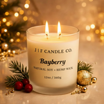 Lit Bayberry soy candle in a frosted glass jar with evergreen sprig, cranberries, and gold accents creating a luxury holiday ambiance, by J | F Candle Co.