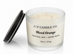 J | F Candle Co. Blood Orange 16 oz luxury soy candle in frosted glass jar with wooden lid beside candle