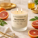 Blood Orange luxury soy candle by J | F Candle Co. in a frosted glass jar surrounded by fresh citrus and elegant gold accents.