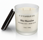 J | F Candle Co. Blue Hawaiian 12 oz luxury soy candle in frosted glass jar with wooden lid beside candle