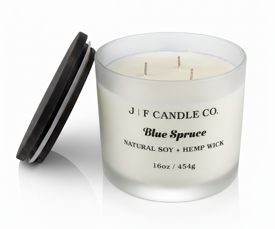 J | F Candle Co. Blue Spruce 16 oz natural soy candle in frosted glass jar with wooden lid beside candle