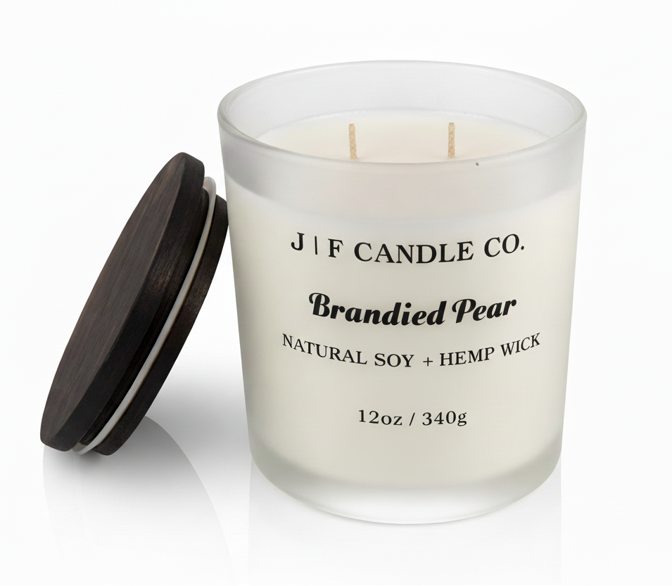 J | F Candle Co. Brandied Pear 12 oz natural soy candle in frosted glass jar with wooden lid beside candle on clean white background