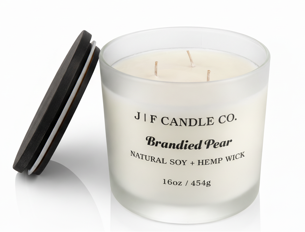 J | F Candle Co. Brandied Pear 16 oz natural soy candle with three wicks in frosted glass jar and wooden lid beside candle on white background