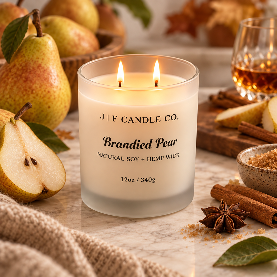 Lit JF Candle Co. Brandied Pear soy candle in a frosted white glass jar with two wicks, styled with fresh pears and warm fall accents.