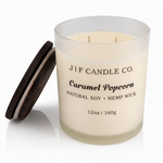 J | F Candle Co. Caramel Popcorn 12 oz natural soy candle with lid off in frosted glass jar and soft reflection on clean white background