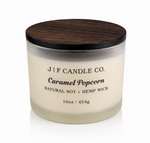 J | F Candle Co. Caramel Popcorn 16 oz natural soy candle in frosted glass jar with wooden lid and soft reflection on clean white background