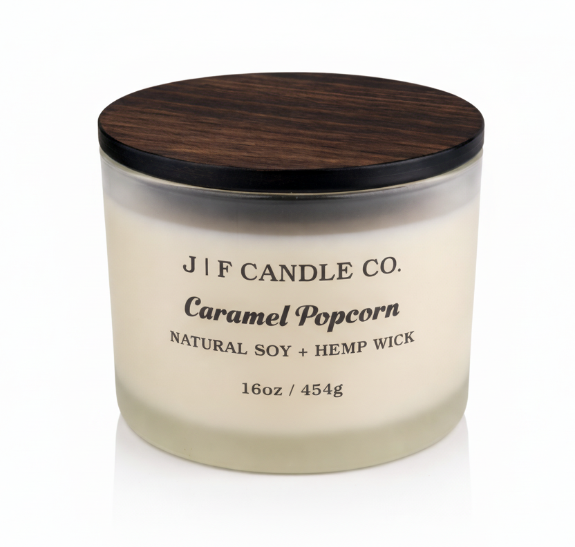 J | F Candle Co. Caramel Popcorn 16 oz natural soy candle in frosted glass jar with wooden lid and soft reflection on clean white background
