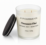 J | F Candle Co. Cinnamon Chai 12oz soy candle in a frosted glass jar with the wooden lid placed beside it on a clean light background with a soft reflection.