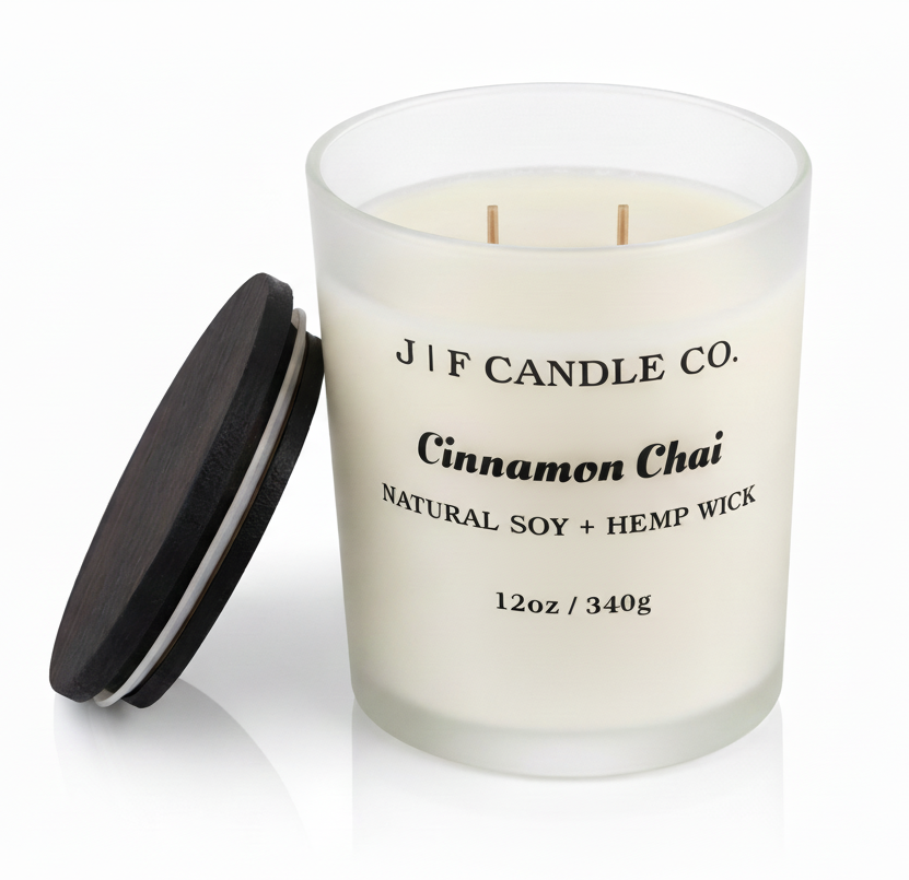 J | F Candle Co. Cinnamon Chai 12oz soy candle in a frosted glass jar with the wooden lid placed beside it on a clean light background with a soft reflection.