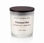 J | F Candle Co. Cinnamon Chai 12oz soy candle in a frosted glass jar with dark wood lid on a clean light background with a soft reflection below.