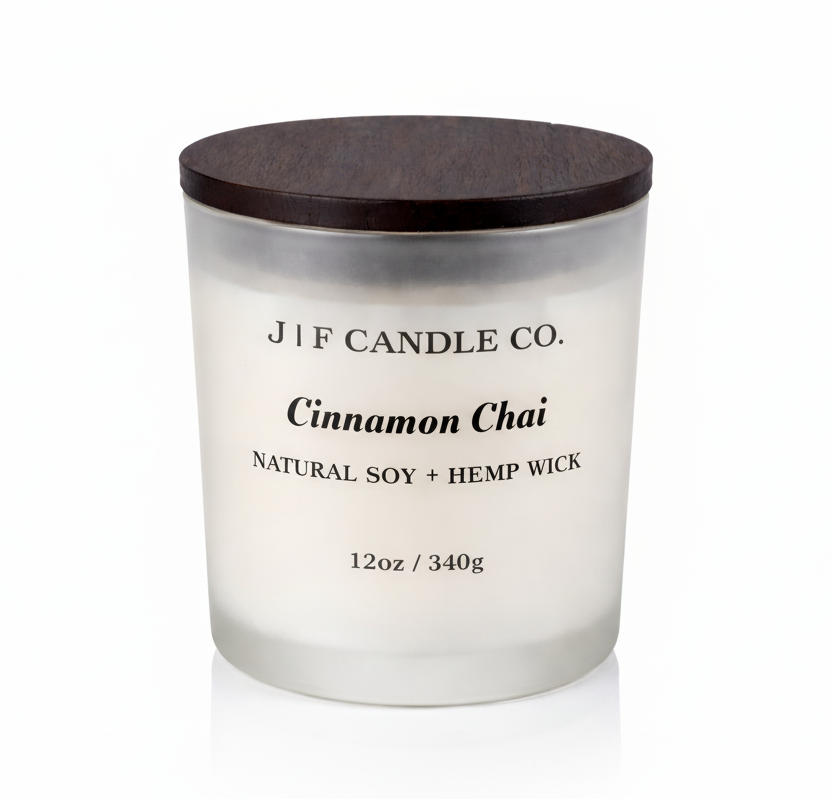 J | F Candle Co. Cinnamon Chai 12oz soy candle in a frosted glass jar with dark wood lid on a clean light background with a soft reflection below.